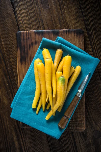 Keltaiset porkkanat sinisellä liinalla — kuvapankkivalokuva