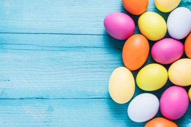 Ahşap masa üzerinde pastel renklerde Paskalya yumurtaları