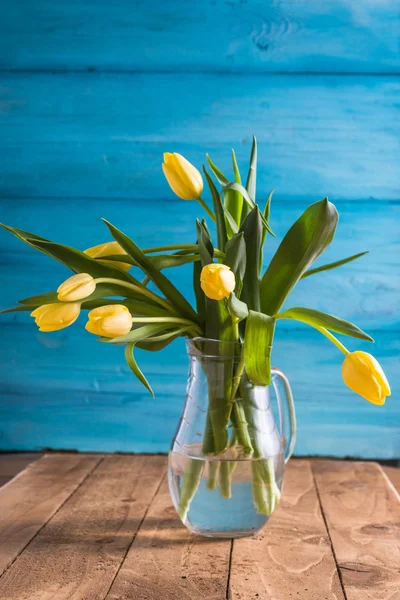 Fresh yellow tulips in vase on wooden background — Stock Photo, Image