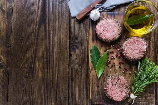 Seasonig minced meat steaks on wooden board — Stock Photo, Image