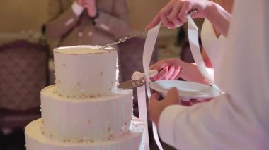 Gelin ve damadın elleri, düğün pastasını keserken, tabağa güzel bir parça düşüyor. Yavaşça.