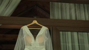 Ahşap bir evin kapısında asılı lüks bir boho tarzı gelinlik. Kırsal bir düğün tarzı. Yakın çekim.