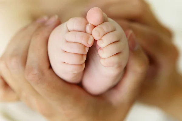 Kinderfüße in den Händen der Mutter — Stockfoto