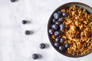 Beyaz mermer arka planda yaban mersinli granola