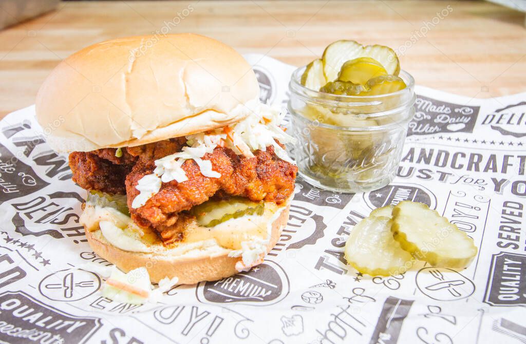 Crispy fried chicken sandwich spicy with sauce coleslaw pickles on light background