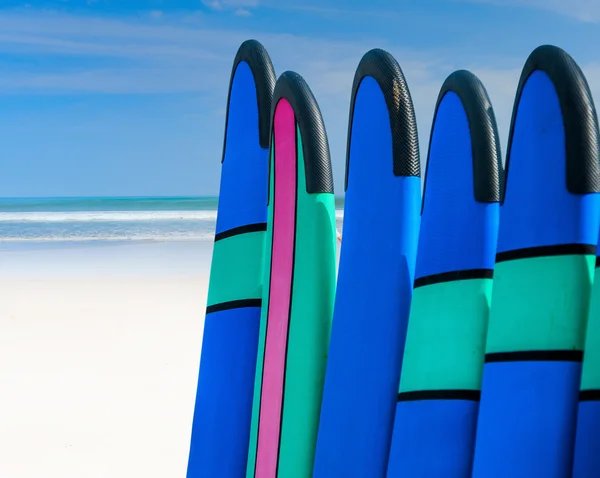 Color surf boards in a stack by ocean — Stock Photo, Image