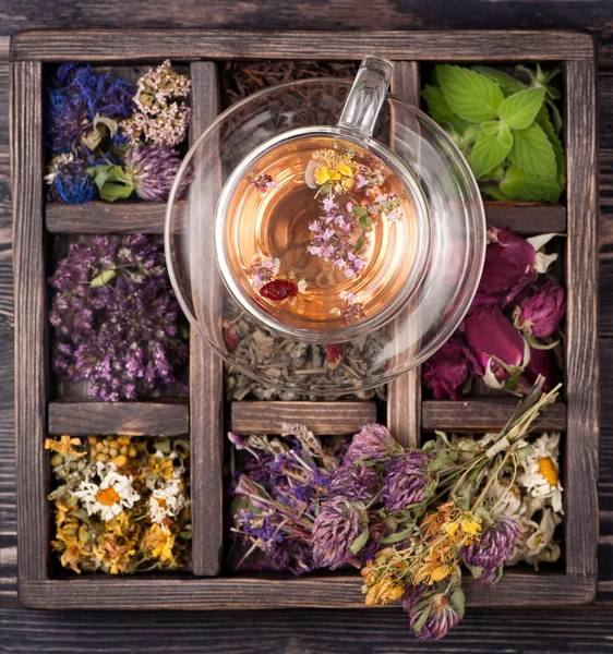 Tea with herbs, flowers and berries and dried herbs in a wooden box