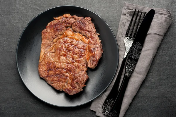 Orta az pişmiş biftek antrikot koyu arka plan üzerinde ızgara. Üstten