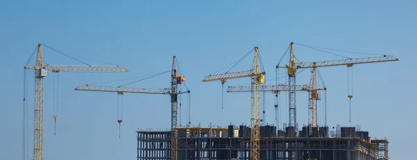 लिफ्ट क्रेन नीले आकाश पर एक नई आवासीय इमारत बनाने वापस — स्टॉक फ़ोटो, इमेज