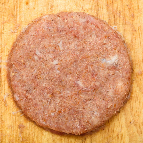 Fresh juicy patty of raw ground beef on a wooden board closeup — Stock Photo, Image