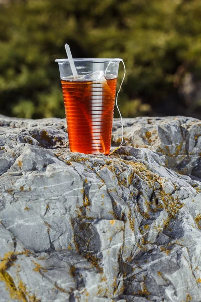 Свежий чай в одноразовой пластиковой чашке с ложкой и мешком на — стоковое фото