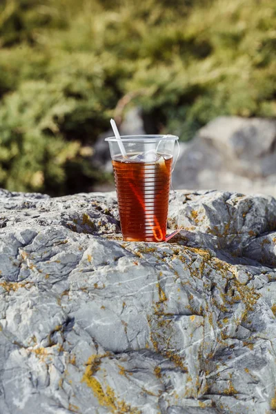 Fresh tea in a disposable plastic cup with a spoon and a bag on — Stock Photo, Image