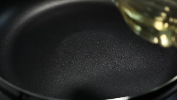 Vegetable oil is pouring from the bottle on a hot pan — Stock Video