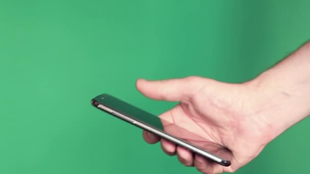 La mano humana con un gadget electrónico sobre fondo verde — Vídeos de Stock