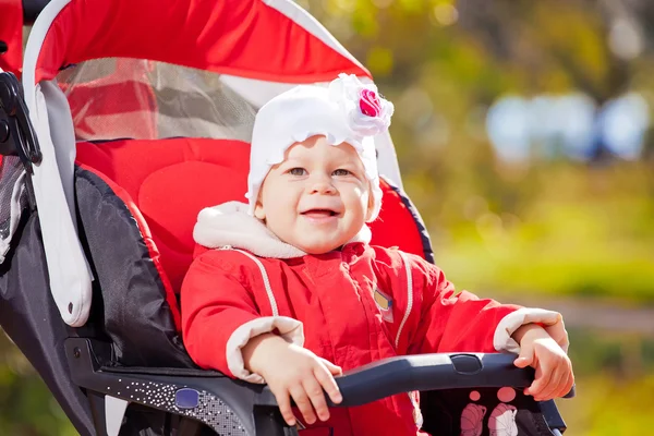 Çocuk arabası park üzerinde kırmızı ceketli güzel küçük kız — Stok fotoğraf