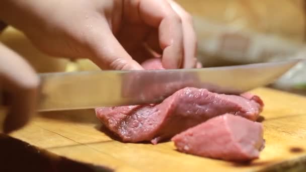 Крупным планом женщина на кухне режет свинину на доске — стоковое видео