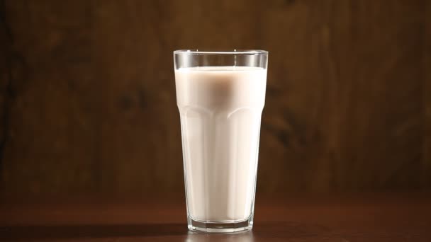 Fiatal férfi keze veszi pohár tej, egy táblából, elszigetelt barna háttér — Stock videók