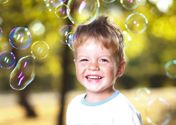 Menino soprando bolhas no parque — Fotografia de Stock