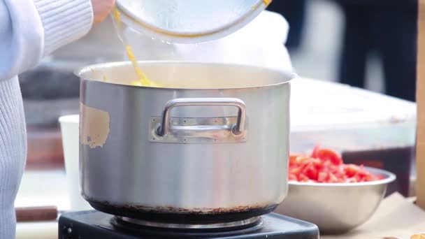 Cauldron with yellow soup cooked over a stove in the street and stirred paddle. — Stock Video