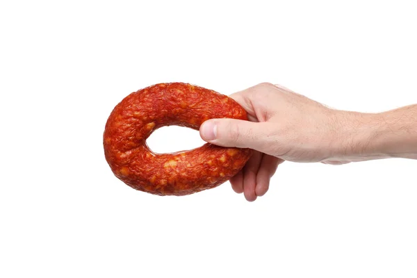 Mão com um anel de salsicha defumada saborosa em um fundo branco — Fotografia de Stock