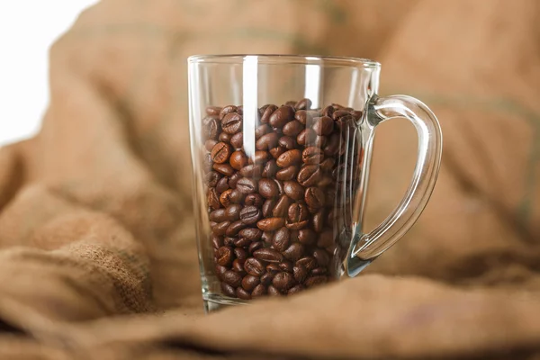Geröstete Kaffeebohnen in einer durchsichtigen Glasschale auf einem Sack — Stockfoto