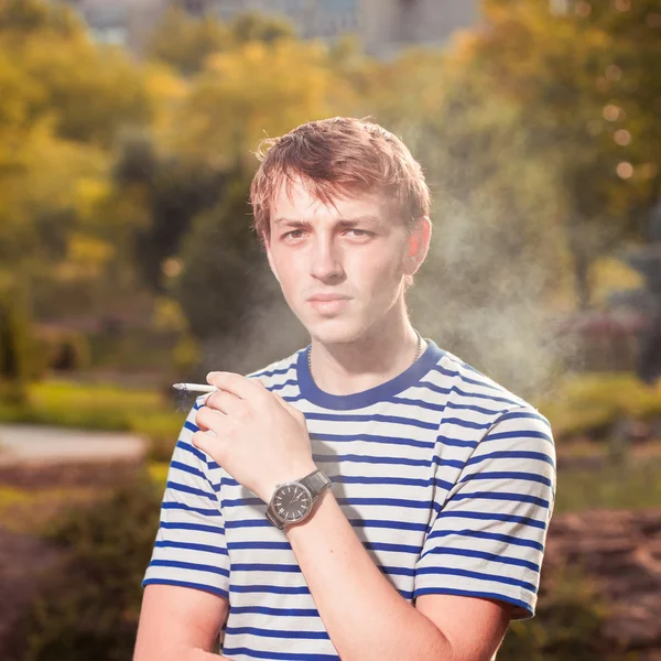 Hipster handsome young man with a cigarette close-up on a backgr — Stock Photo, Image