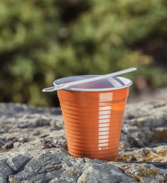 Tasse à café en plastique brun avec une cuillère sur un rocher sur un fond — Photo