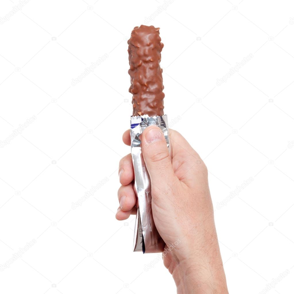 chocolate bar with nuts in foil, in hand isolated on white backg