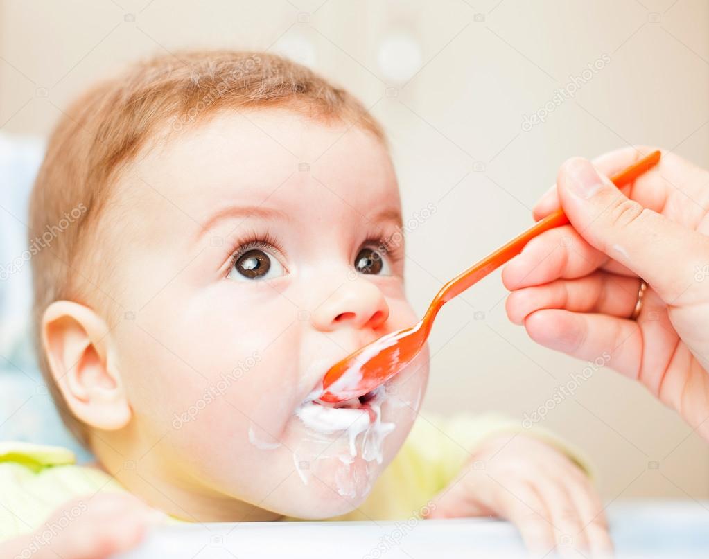 very little kid eats fresh tasty nutritious curds on highchair