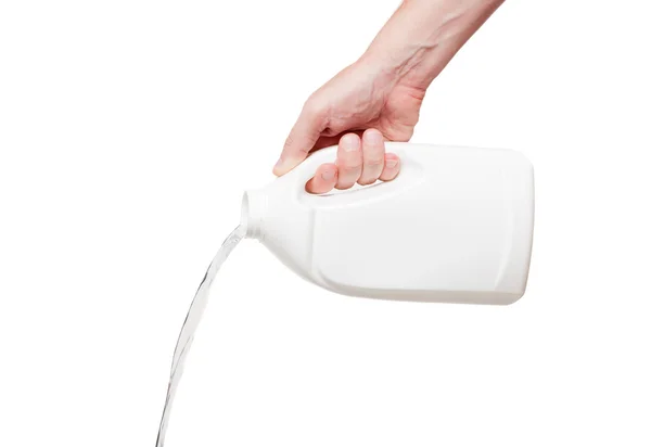Ρέει έξω υγρό από λευκό πλαστικό μπουκάλι στο χέρι, απομονωμένη σε — Φωτογραφία Αρχείου