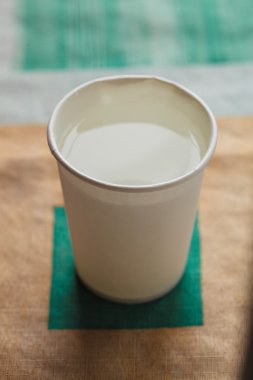 Kağıt bardak masanın üzerine parlak arka plan üzerinde beyaz bir renk