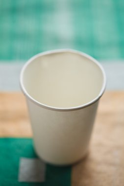 Kağıt bardak masanın üzerine parlak arka plan üzerinde beyaz bir renk