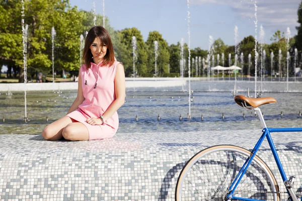 Atrakcyjna dziewczyna siedzi na fontannie — Zdjęcie stockowe
