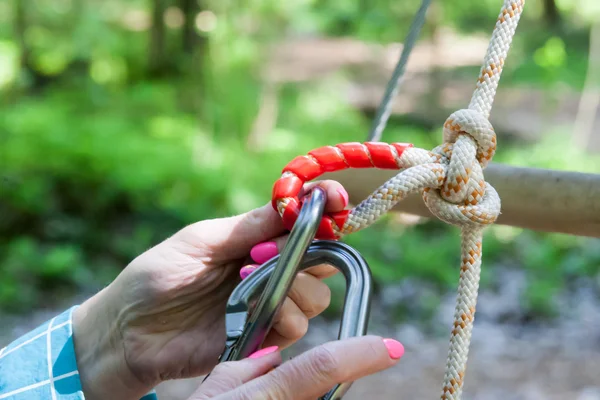 Händerna på den flicka klängande karbiner till en kabel — Stockfoto