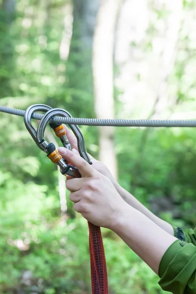 Händerna på den flicka klängande karbiner till en kabel — Stockfoto