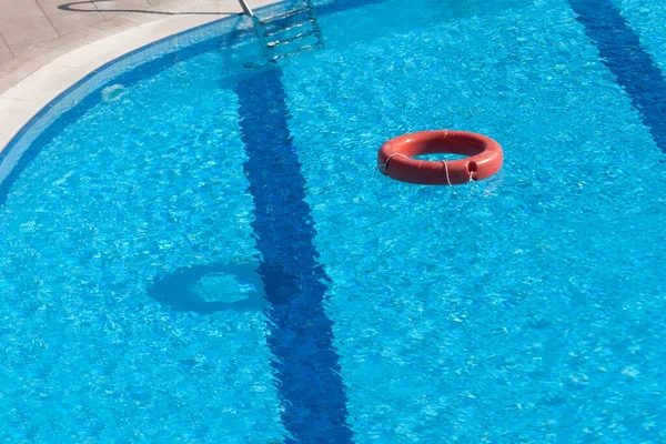 澄んだ夏の日に美しい青い水でホテルのプールに浮かぶ赤い救命艇 — ストック写真