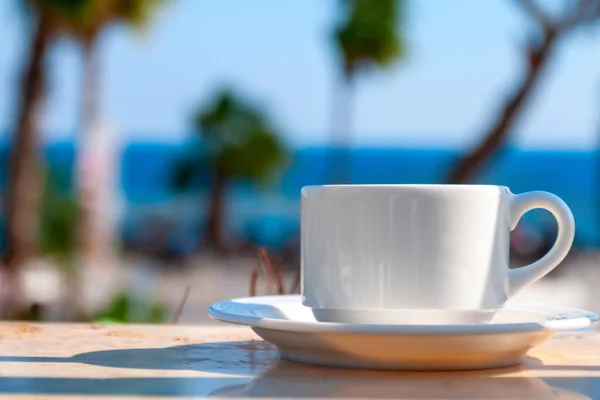 夏の晴れた日にヤシの木を背景にカフェのテーブルの上にコーヒーとマグカップ ストック写真