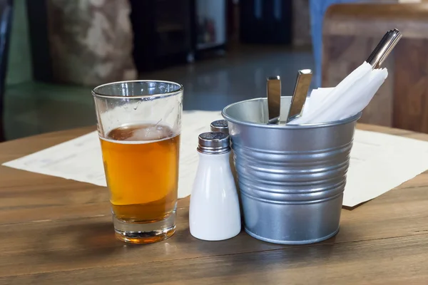 Vaso con cerveza en una mesita de madera en la cafetería —  Fotos de Stock