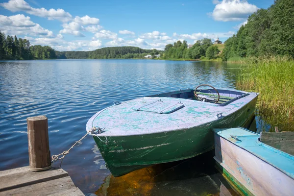 Gamla motorbåt knuten till en träbrygga på sjön — Stockfoto