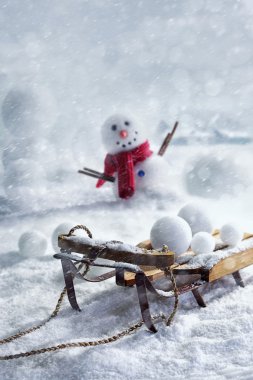 Wooden sleigh and snowballs with snowman  clipart
