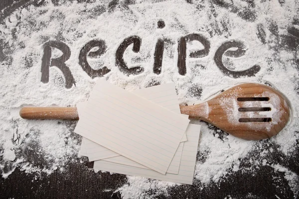 Word recipe written in white flour and spatula on wood — Stock Photo, Image