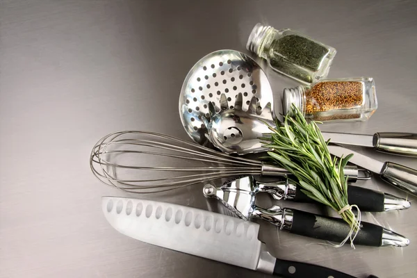 Kitchen utensils and herbs on stainless steel — Stock Photo, Image