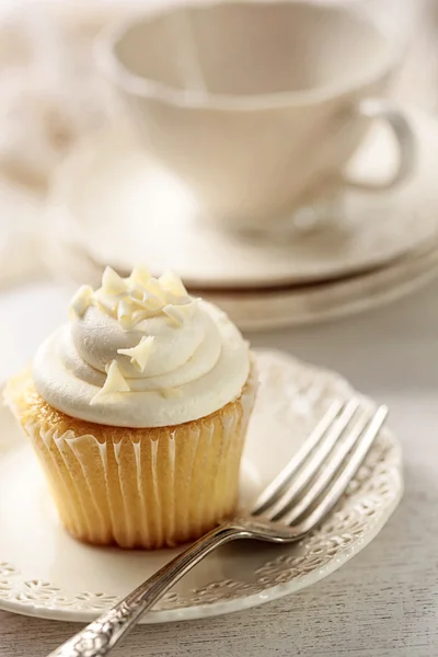 Closeup of vanilla cupcake with tea cup — Stock Photo, Image