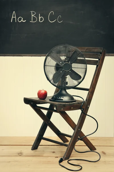 Oude ventilator met apple op stoel in school kamer — Stockfoto