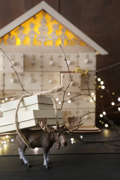 Speelgoed moose uitvoering cadeau met houten huis in achtergrond — Stockfoto