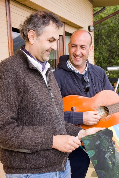 Man målar en bild när hans vän som spelar gitarr — Stockfoto