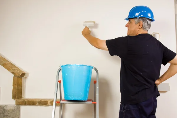 Travailleur peint le mur avec une brosse — Photo