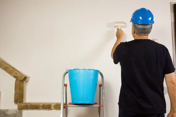 Travailleur peint le mur avec une brosse — Photo