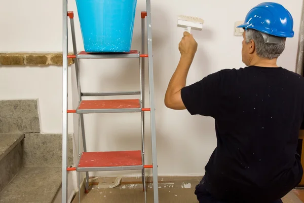 Travailleur peint le mur avec une brosse — Photo