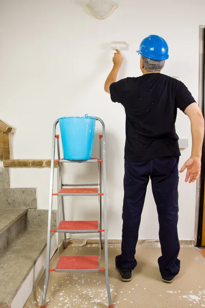 Travailleur peint le mur avec une brosse — Photo